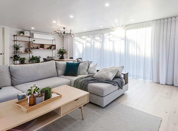 Designer living room with grey sofa and double curtains the full length of the wall. 