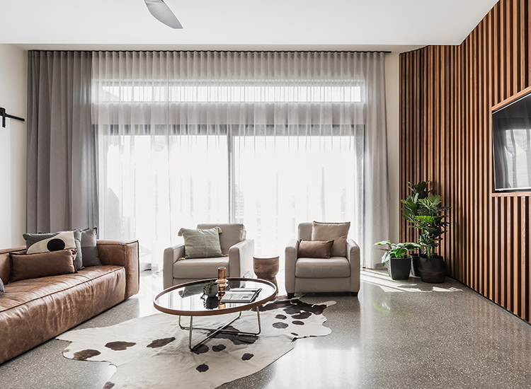 A large, contemporary living room featuring layered white sheer curtains and grey blockout curtains installed behind a ceiling pelmet.