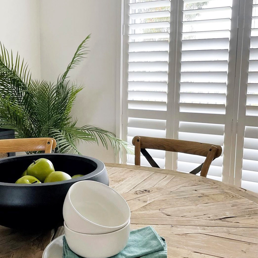 Beautiful plantation style dining room with table detail and plantation shutters on the window. 