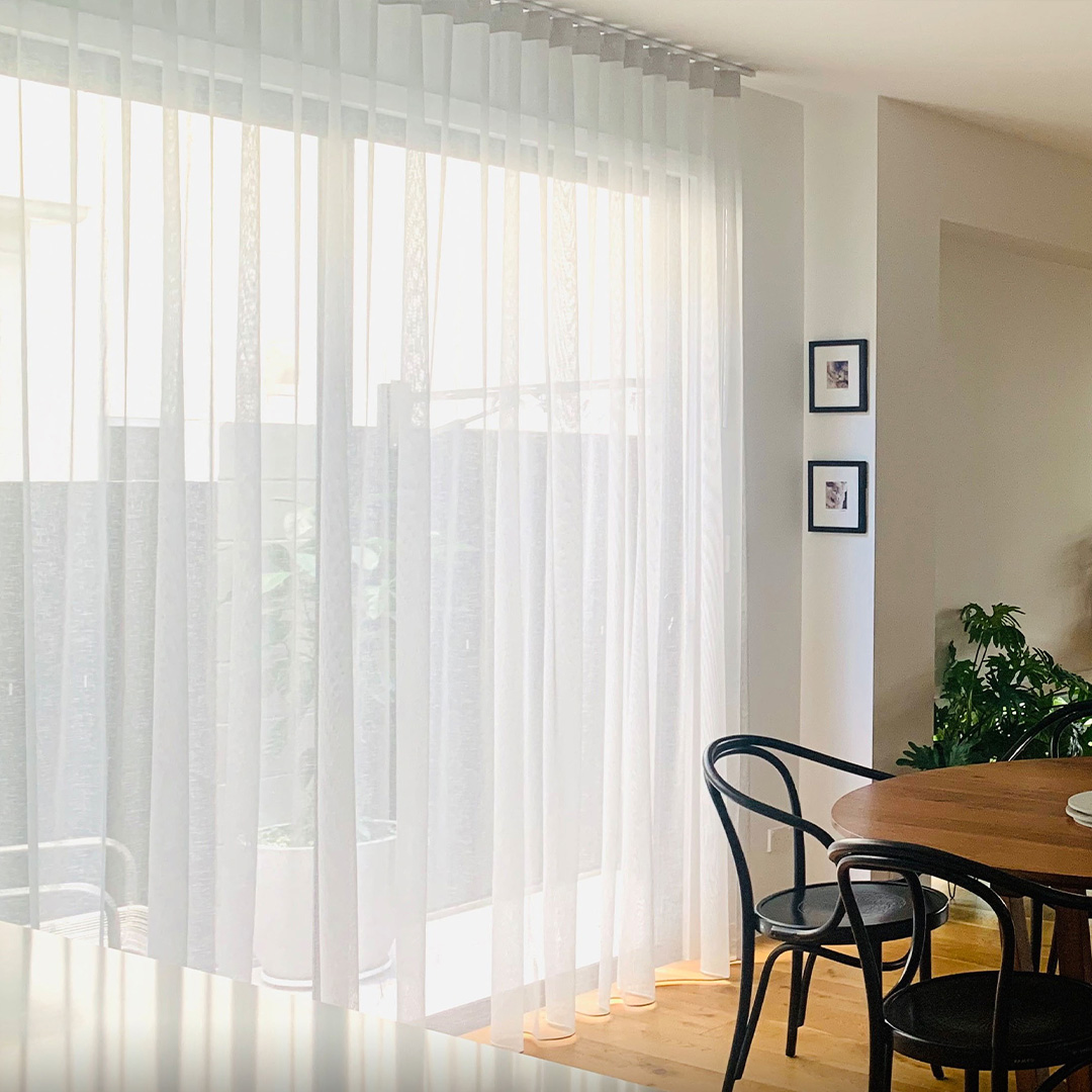 Sheer curtains installed over sliding doors next to an open plan dining room