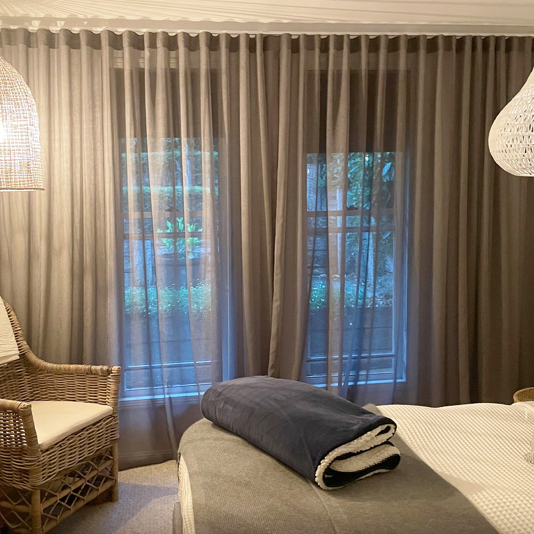 Cosy master bedroom with dark grey sheer curtains on the windows. 