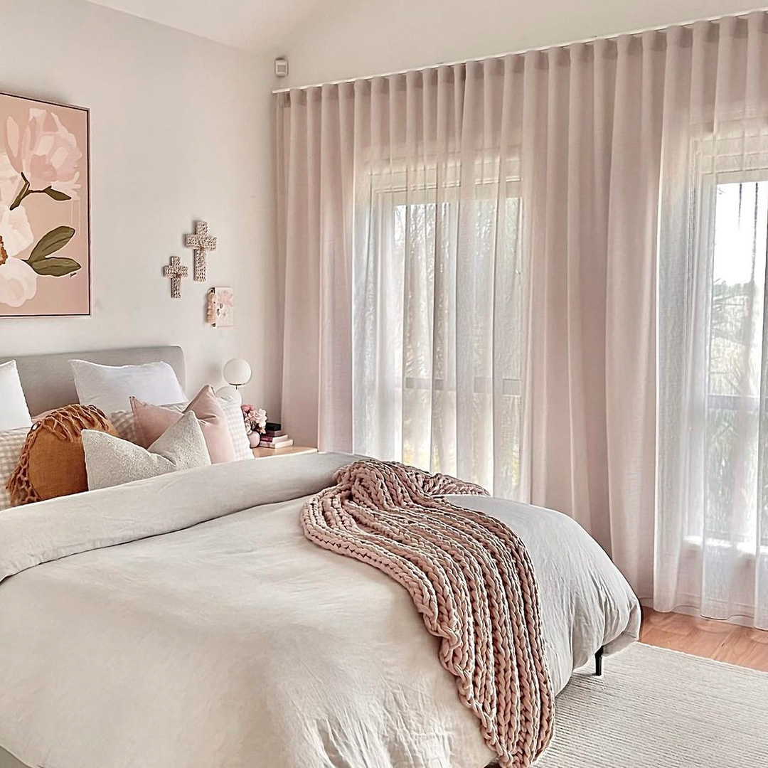 Beautiful contemporary bedroom with warm, soft colours and sheer curtains to match.